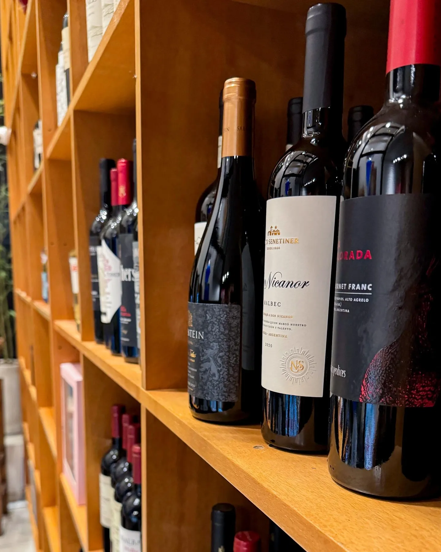 Interior de la vinoteca 30&UNO: estantería de madera clara con botellas de Nieto Senetiner Don Nicanor, Cabernet Franc Las Perdices y otras